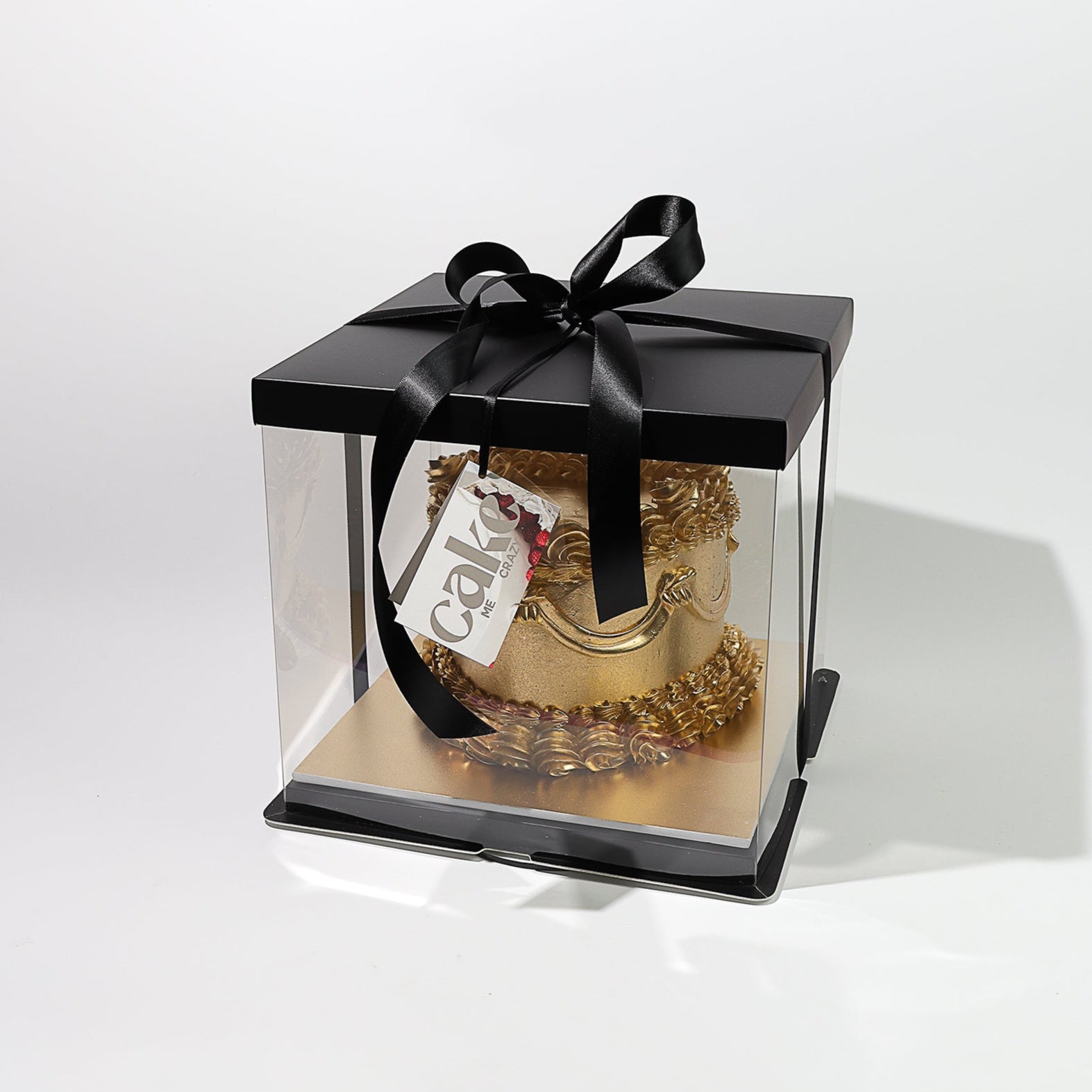 solid gold birthday cake packaged in a clear and black cake box. 