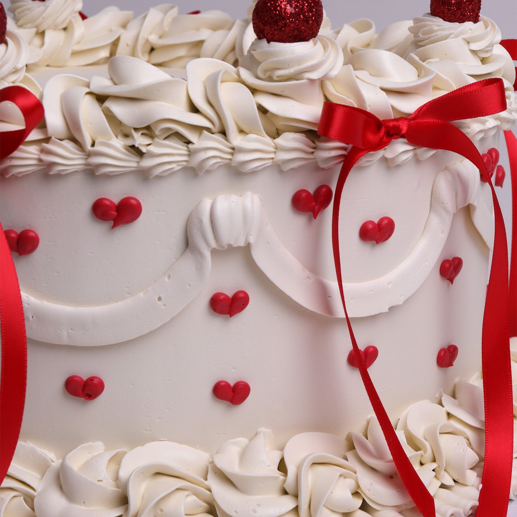 Heart-shaped vintage cake with cherries, red bows and piped cream