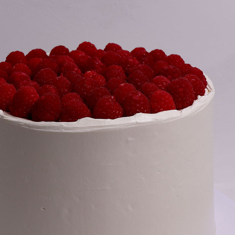 White cake with red raspberries on a white background