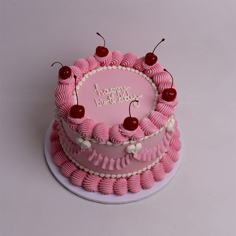 Pink vintage birthday cake with cherry decorations on a white background