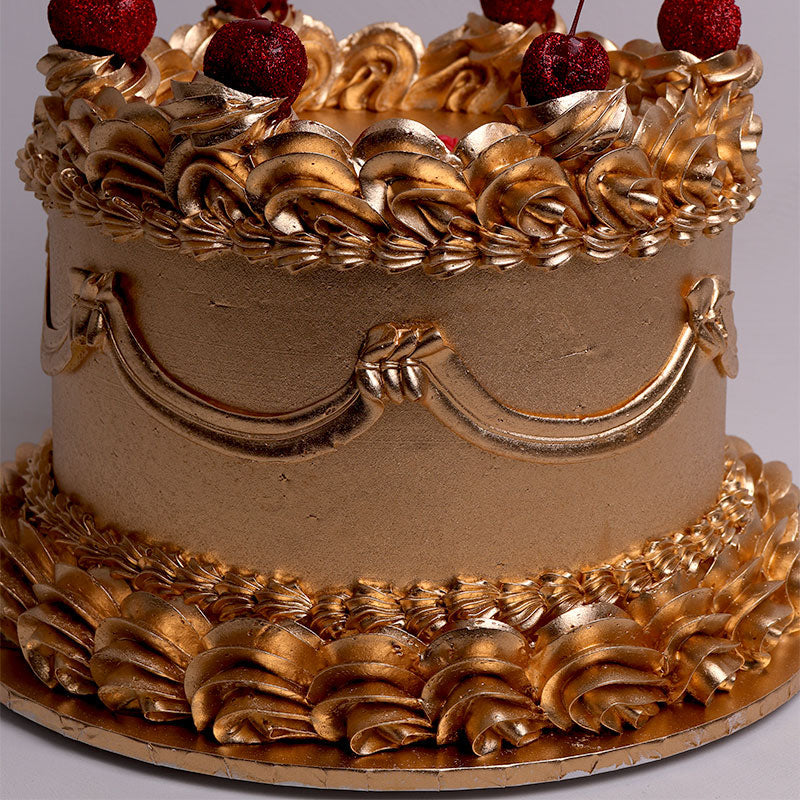 vintage cake with gold icing and cherries on a gray background
