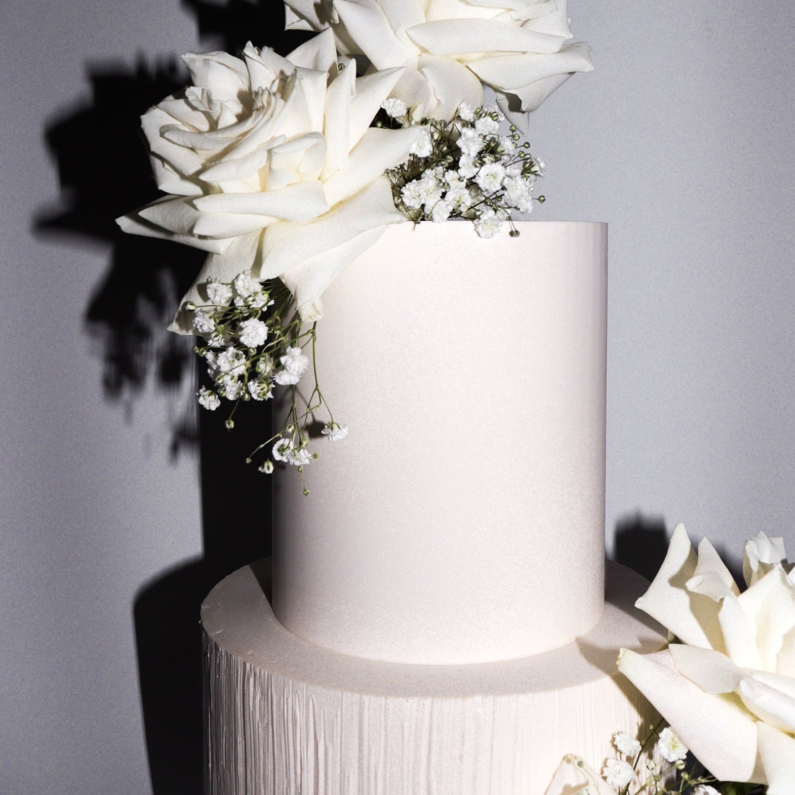 White wedding cake with floral decorations on a gray background