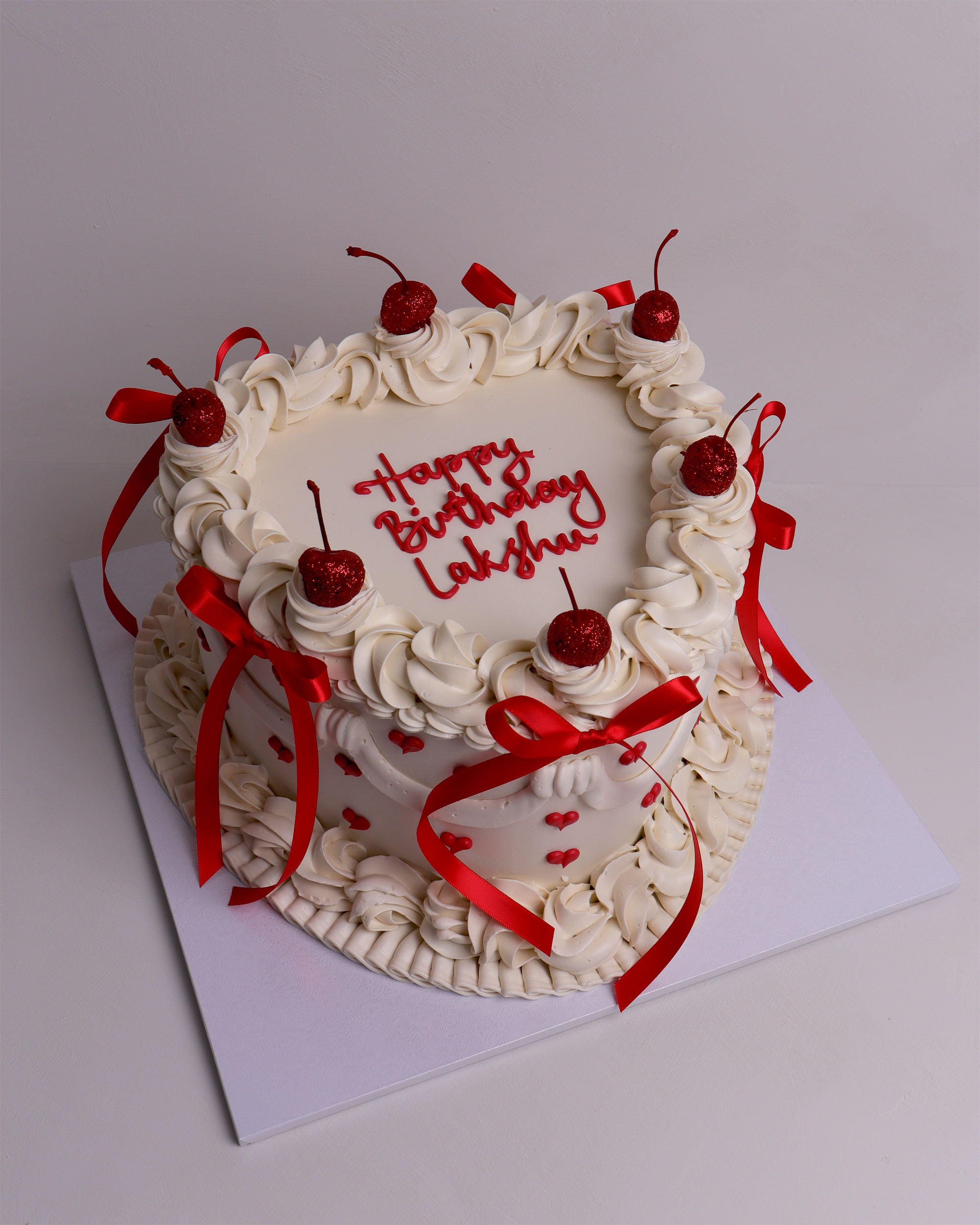 Heart-shaped retro heart cake with piped buttercream, red ribbon bows, cherries and mini heart details – perfect for birthdays and romantic celebrations in Melbourne